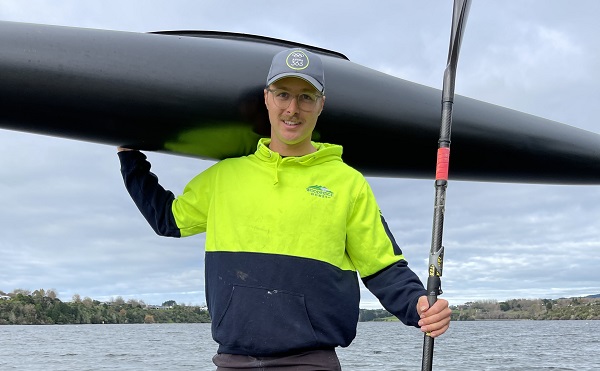 Kurtis Imrie holding a canoe over his shoulder on the dock